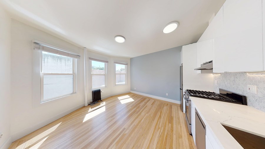 A kitchen with white cabinets and a wooden floor.
